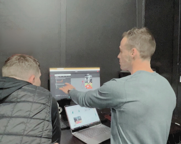 Coach instructing player with swing analytics information on computer